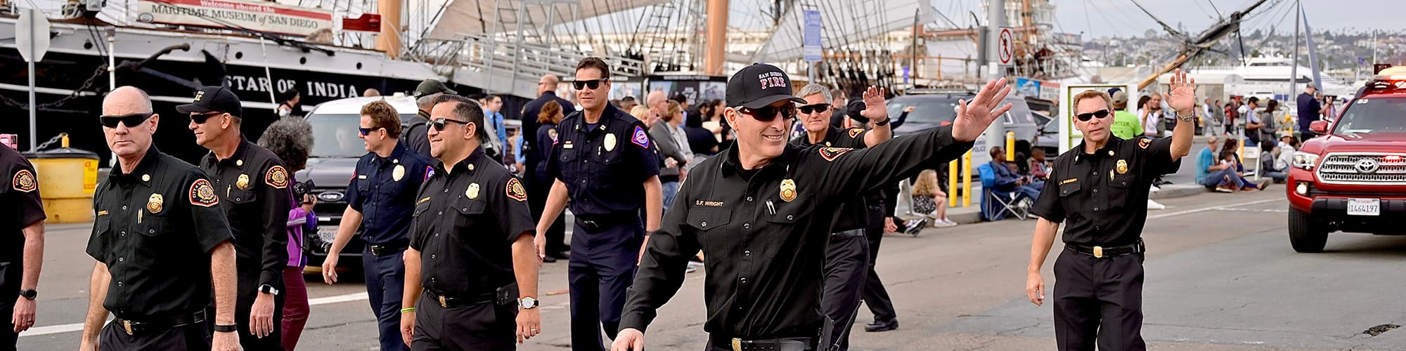 San Diego police and firefighters wave in a parade next to the Star of India old boat