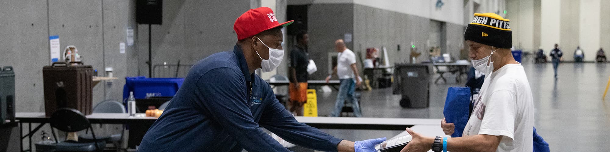 Men in medical masks hand each other items